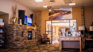 A lobby with a stone fireplace, a television, a large window, and a reception desk. - Inn at the Canyons (Monticello)