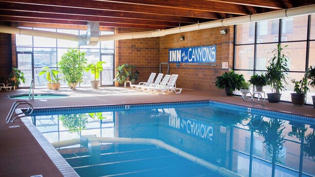 An indoor swimming pool with lounge chairs and potted plants. - Inn at the Canyons (Monticello)