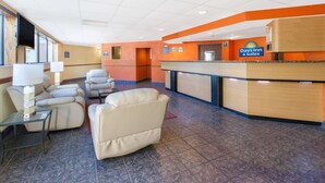 A hotel lobby with a reception desk, seating area, and a television mounted on the wall. - Days Inn & Suites by Wyndham Madison Heights MI (Madison Heights)