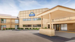 A Days Inn & Suites building with a large parking lot, a covered entrance, and a sign indicating the hotel name. - Days Inn & Suites by Wyndham Madison Heights MI (Madison Heights)