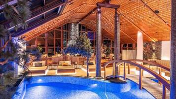 Un área de piscina con techo de madera, un pilar de piedra y una zona de estar con sillas y una mesa.