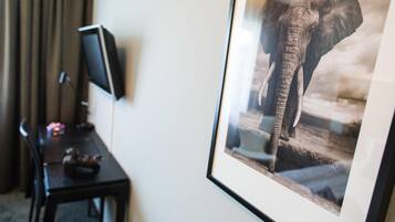 A framed photograph of an elephant on a wall, a desk with a computer, and a chair.