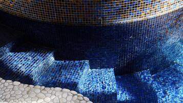 Relax by the pool surrounded by a vibrant mosaic tile design and smooth pebbles.