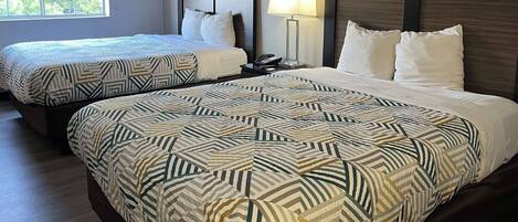 Habitación de hotel con dos camas, cada una con ropa de cama estampada y cabeceros de madera.
