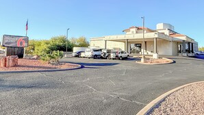 A motel with a sign indicating it is number 6, parked cars, and a clear blue sky. - Motel 6 Tucson, AZ – Airport / Kino Sports Complex (Tucson)