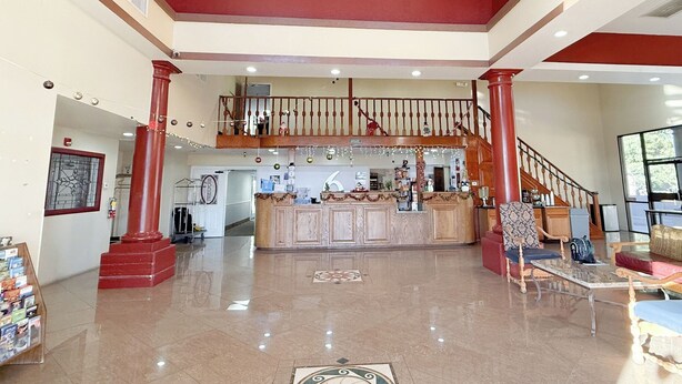 A spacious lobby with a chandelier, a reception desk, and a staircase leading to an upper level. - Motel 6 Tucson, AZ – Airport / Kino Sports Complex (Tucson)