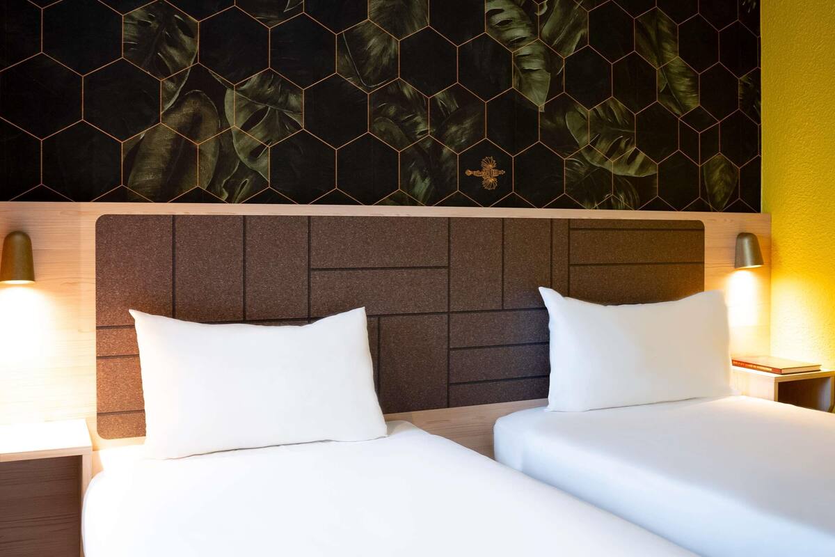 Ein Hotelzimmer mit zwei Betten, einem Holzkopfstück und einer Wand mit sechseckigem Muster.