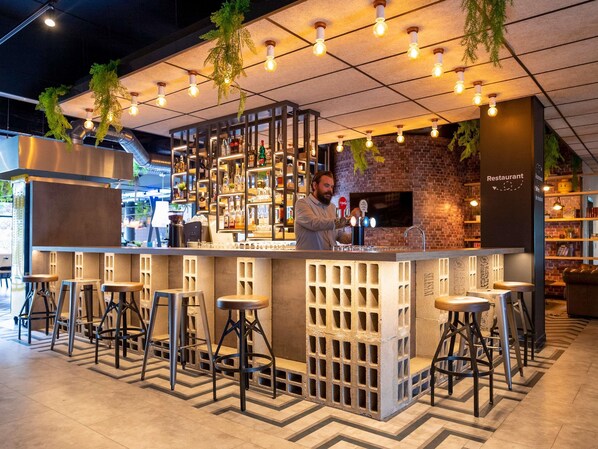 A bar area with stools, a bartender, and a brick wall. - ibis Styles Strasbourg Nord Palais des Congrès (Schiltigheim)
