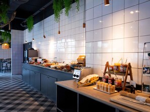 Une cuisine moderne avec un carrelage à motifs, un buffet garni de divers aliments et des plantes suspendues.