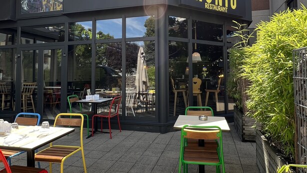 Ein Außenbereich eines Restaurants mit Tischen und Stühlen, umgeben von Gebäuden.