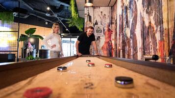 A pool table with a vintage design, a number 89 sign, and a mural in the background.