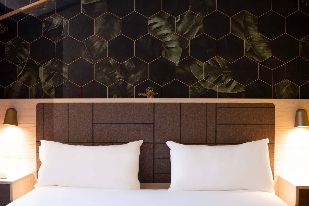 Ein Hotelzimmer mit einem Bett, zwei Nachttischlampen und einer Wand mit sechseckigem Muster.