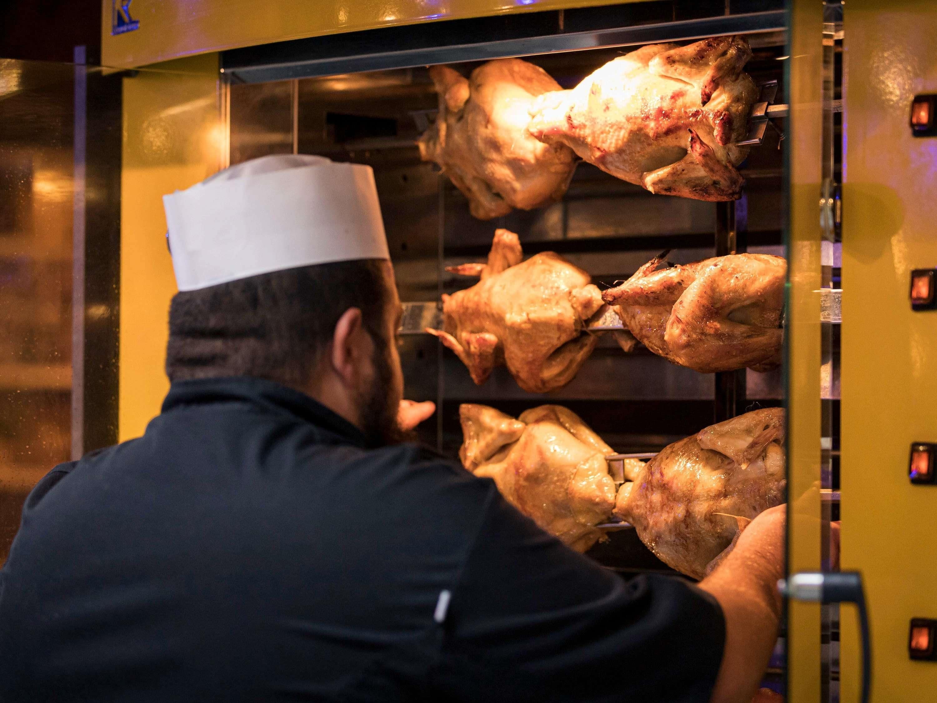 Um cozinheiro de uniforme prepara um grande assador em uma cozinha.