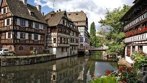 Ein traditionelles Fachwerkhäuschen mit einem Fluss davor.