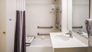 A bathroom with a white sink, a mirror, a shower, and a hand dryer.