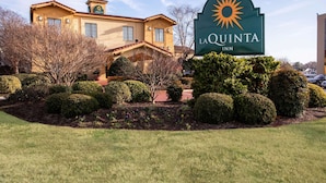 A hotel with a sun logo, named La Quinta Inn, surrounded by well-maintained landscaping and a clear sky. - La Quinta Inn by Wyndham Norfolk Virginia Beach (Virginia Beach)
