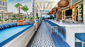 A rooftop bar with a pool, lounge seating, and a bar area with stools and a bar counter.