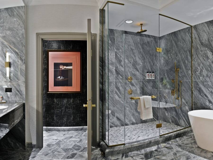 Un baño moderno con pared de mármol, cabina de ducha de vidrio y bañera independiente.