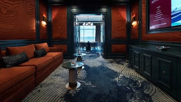 A hotel lobby with a red sofa, a coffee table, and a view of the ocean through a large window.