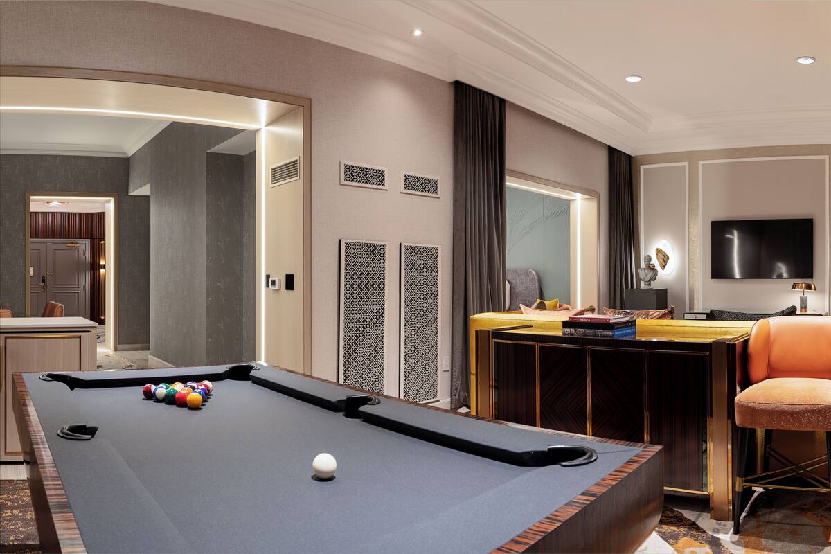 A pool table with balls, a bar area, a television, and a seating area with a chair.