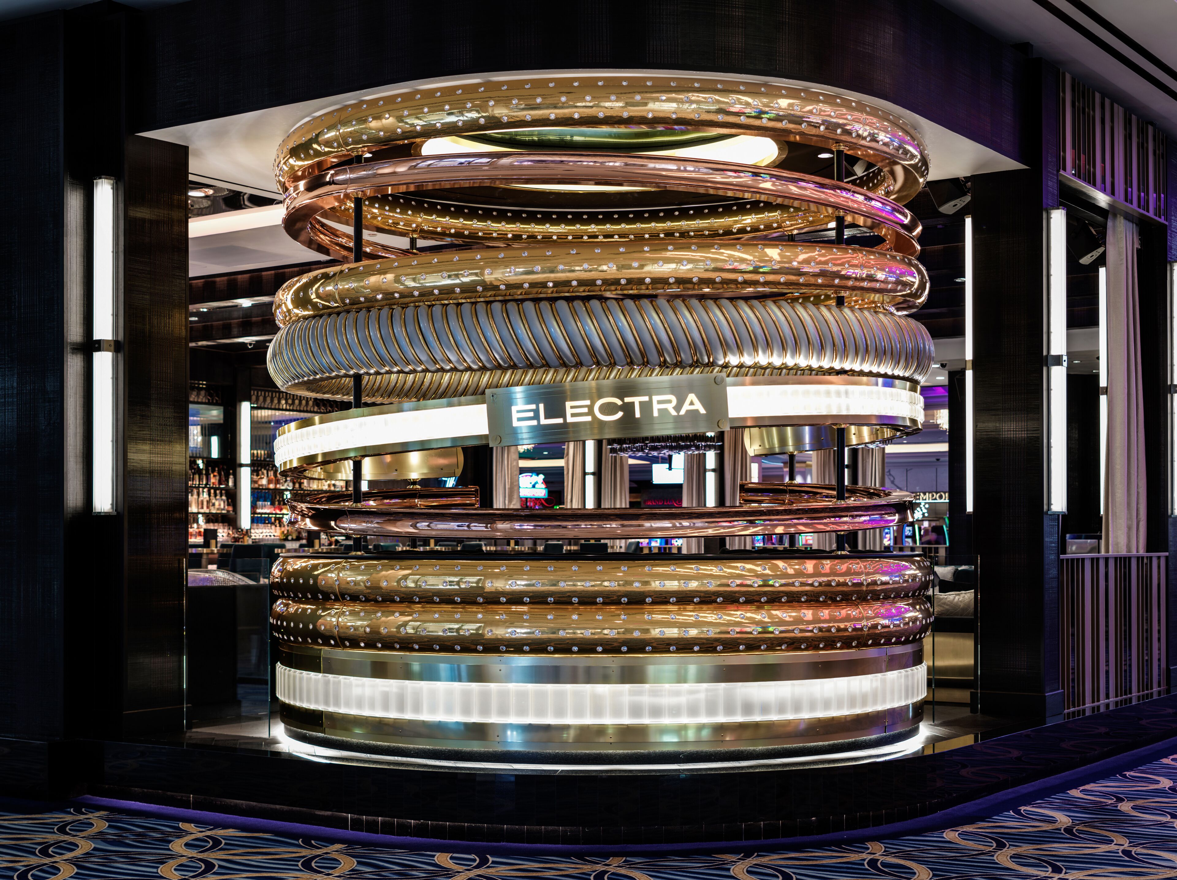 A circular, multi-tiered structure with the word "ELECTRA" visible, surrounded by a dark interior with patterned flooring.