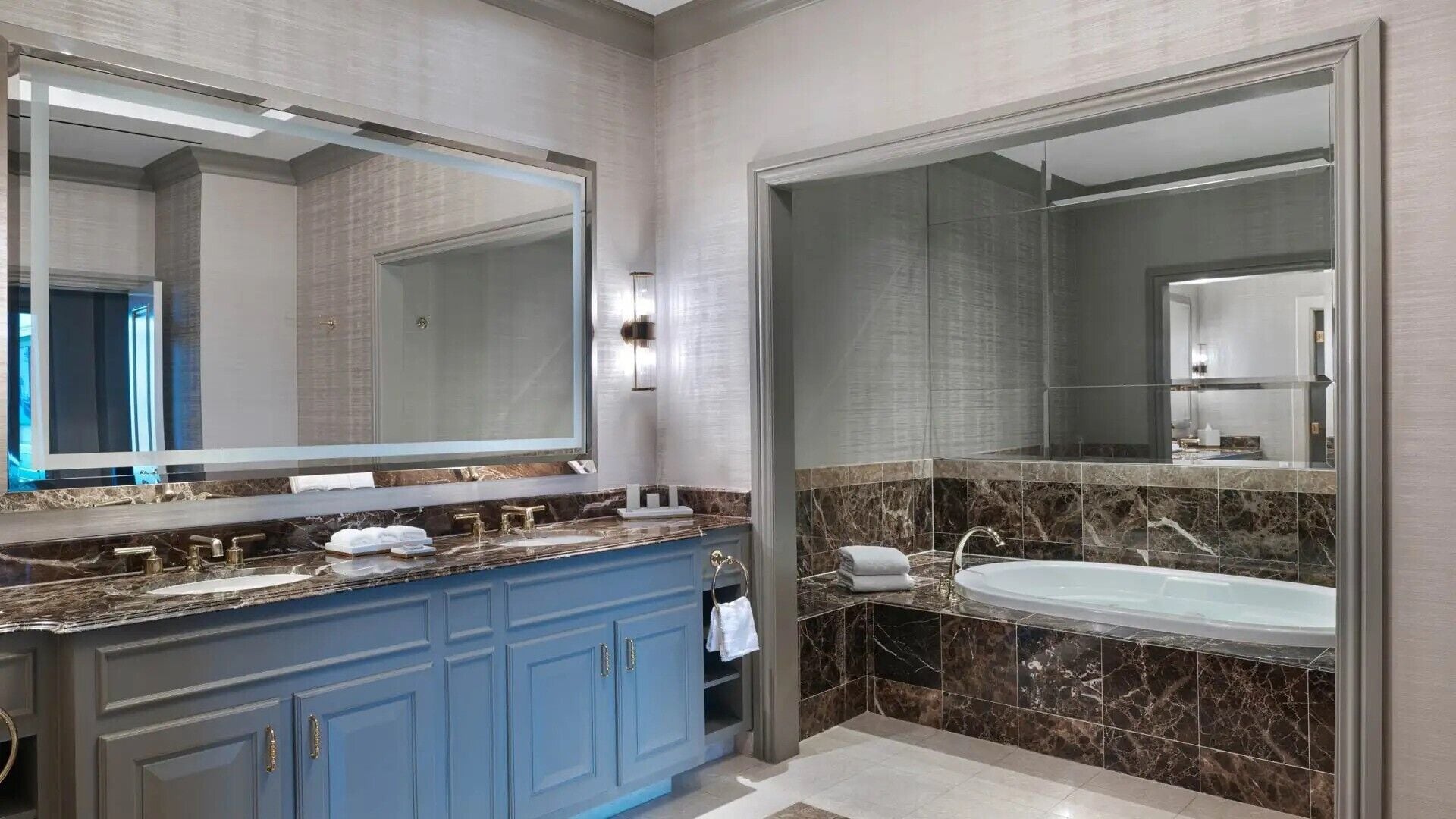 Ein modernes Badezimmer mit einem großen Spiegel, einer Badewanne und einem Waschtisch mit Marmorplatte.