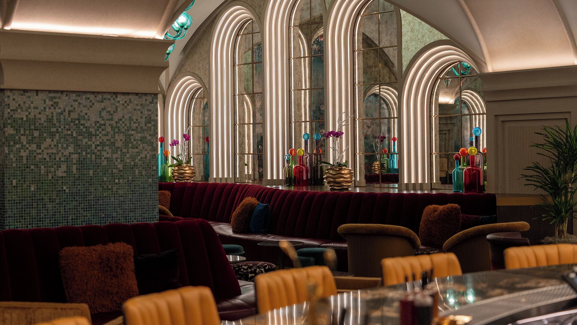 Un restaurant doté de grandes fenêtres en arc, de sièges confortables et d’un mur recouvert de carreaux.