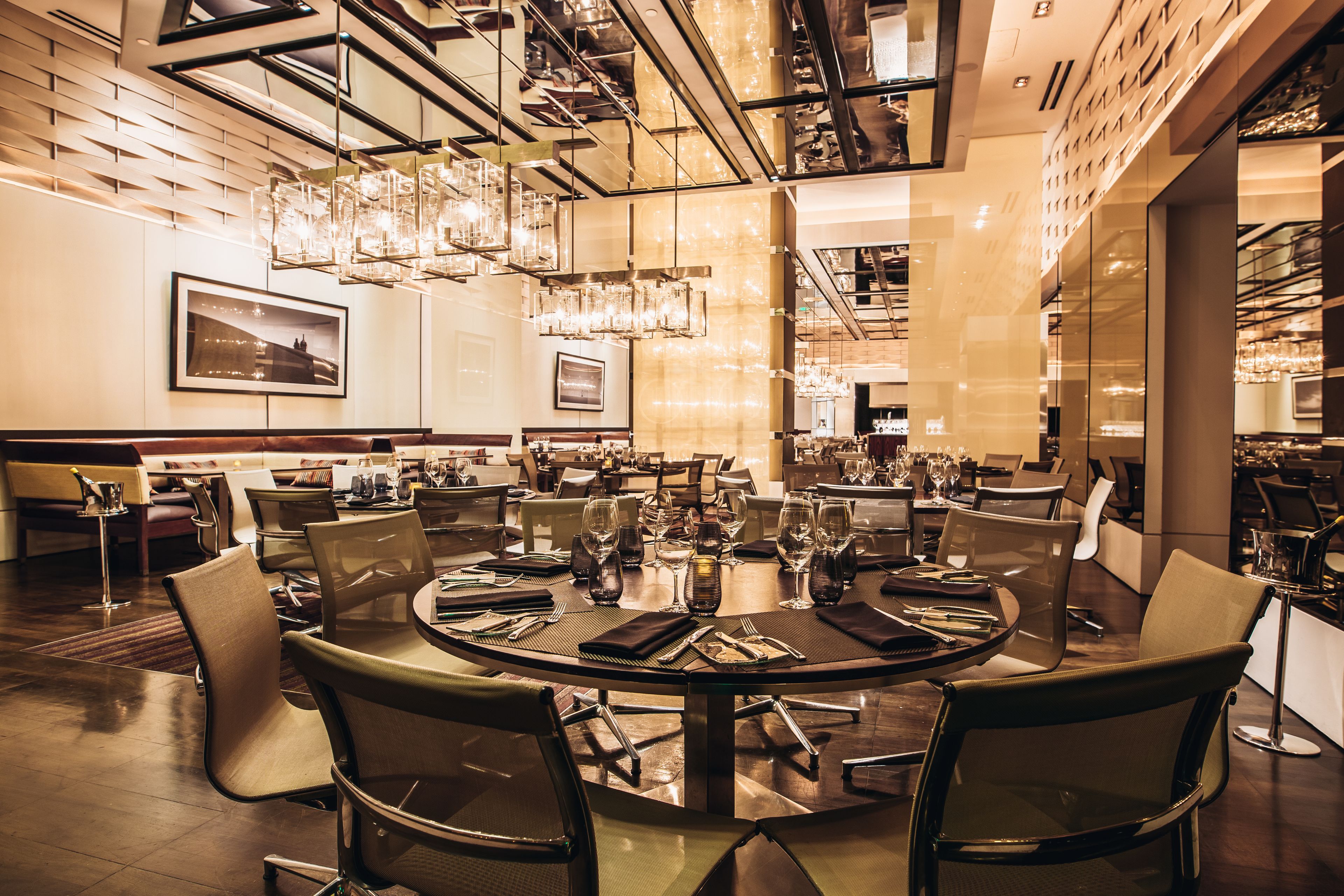 A modern dining area with round tables, chairs, and chandeliers.