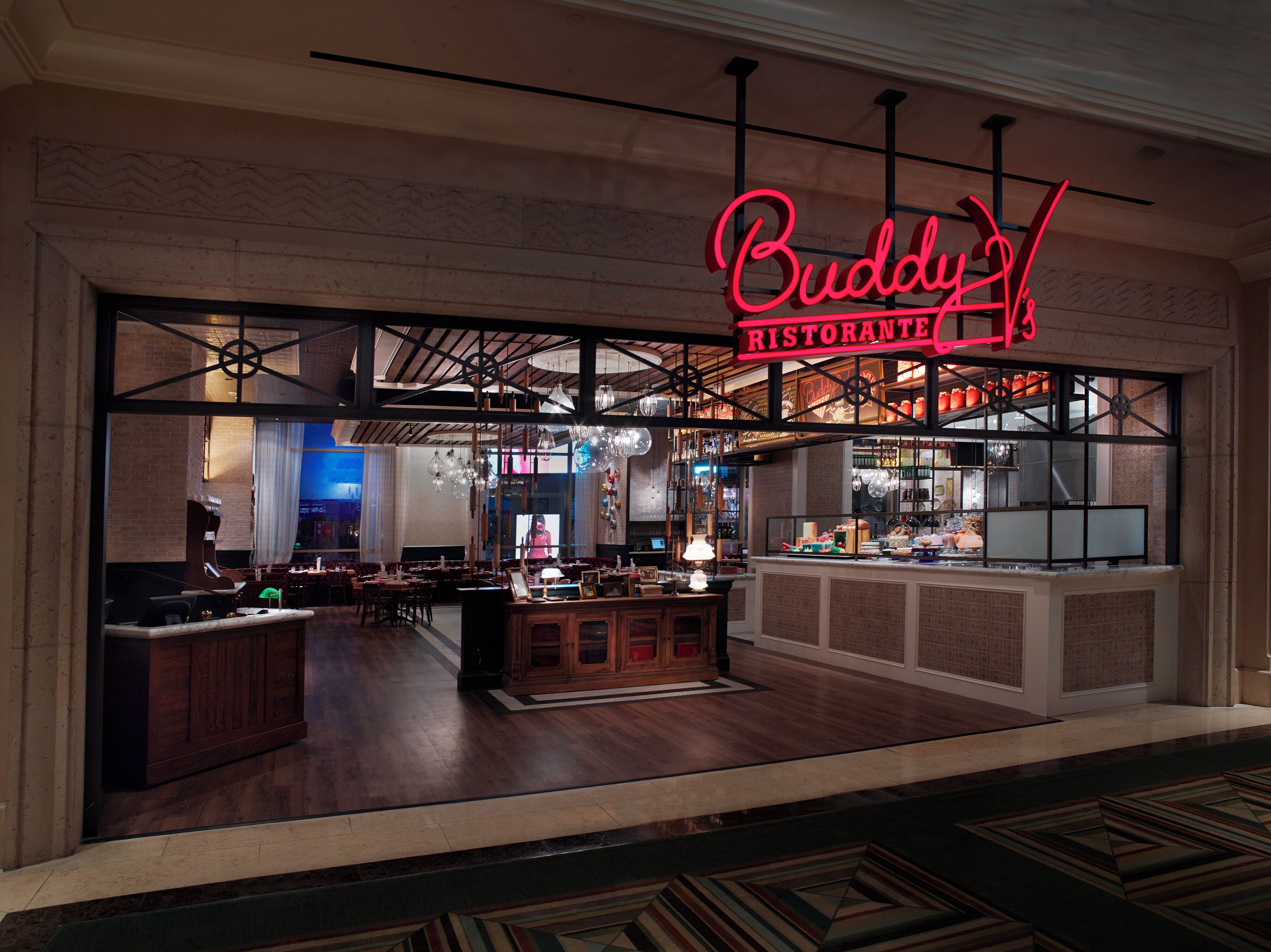 A restaurant with a neon sign reading "Buddy Ristorante" and a bar area visible through the window.
