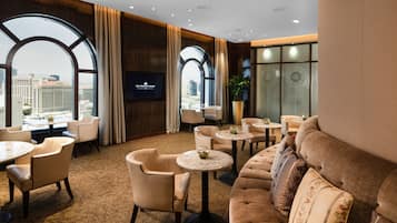 Un moderno hall de hotel con un amplio ventanal de arco, asientos cómodos, televisor de pantalla plana y vistas a la ciudad.