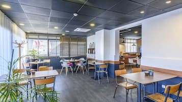 Un interior de restaurante moderno con mesas, sillas y plantas en macetas.