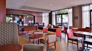 A hotel lobby with seating areas, a kitchenette, and large windows.