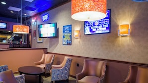 A bar area with leather chairs, a round table, and a television screen.