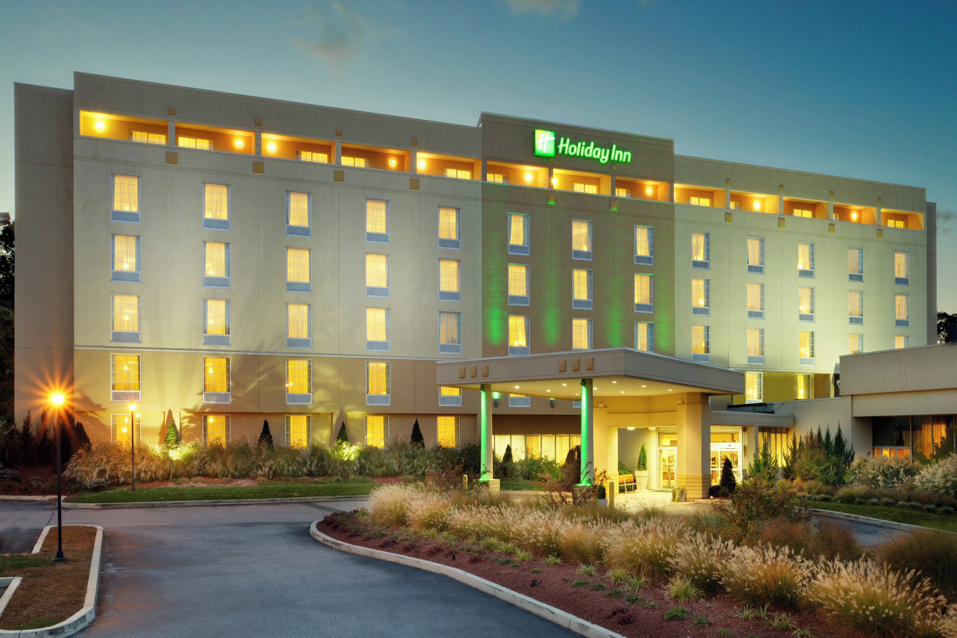 Un hotel Holiday Inn con fachada moderna, múltiples ventanas y una entrada bien iluminada.
