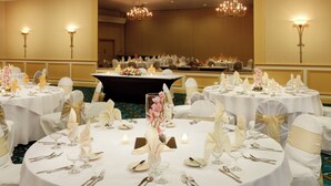 A banquet hall with round tables set for a formal event, featuring white tablecloths, silverware, and floral centerpieces.