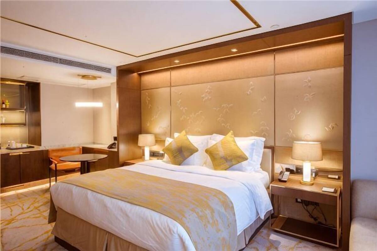 A hotel room with a large bed, bedside tables, a desk, and a chair.