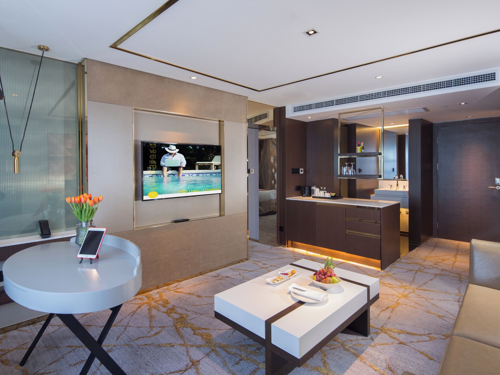 Ein modernes Hotelzimmer mit Fernseher, Essbereich, Küche und Bad.