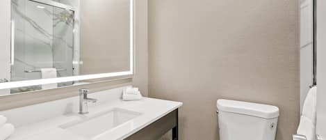 Un baño moderno con un espejo grande, un lavabo y un inodoro.
