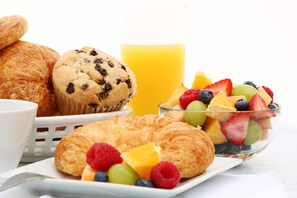 A breakfast setting with croissants, muffins, and a fruit bowl.