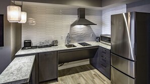 A modern kitchen with a stainless steel refrigerator, a built-in oven, and a hexagonal tile backsplash.