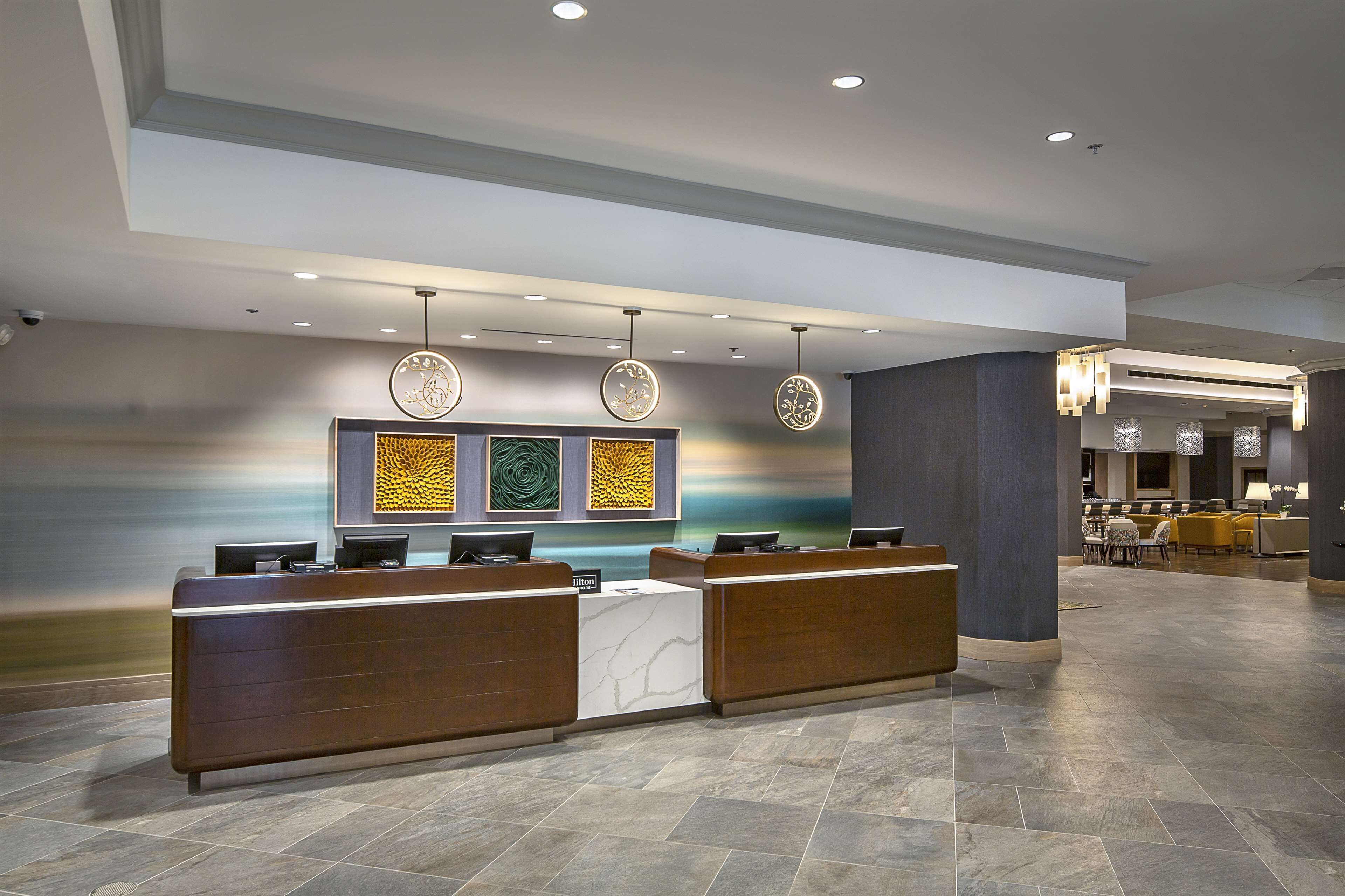 Ein Hotel-Empfangsbereich mit modernem Design, der eine Rezeption, eine Sitzecke und Wanddekoration umfasst.