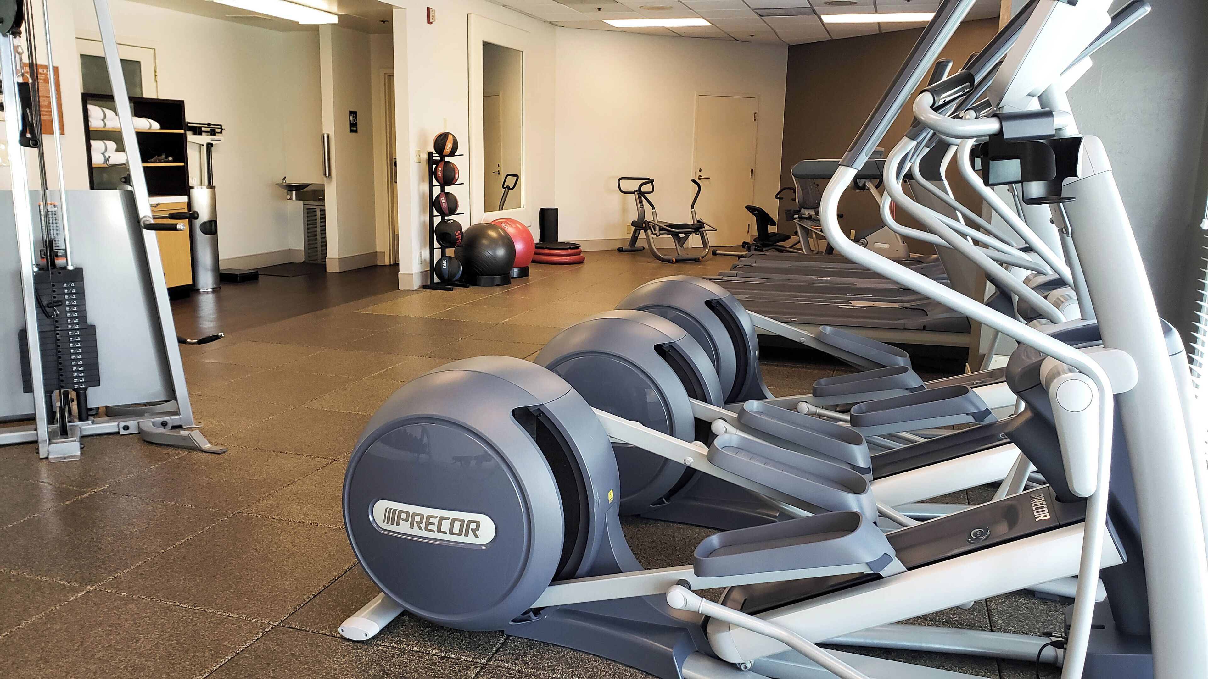 A gym with treadmills, weight machines, and exercise balls.