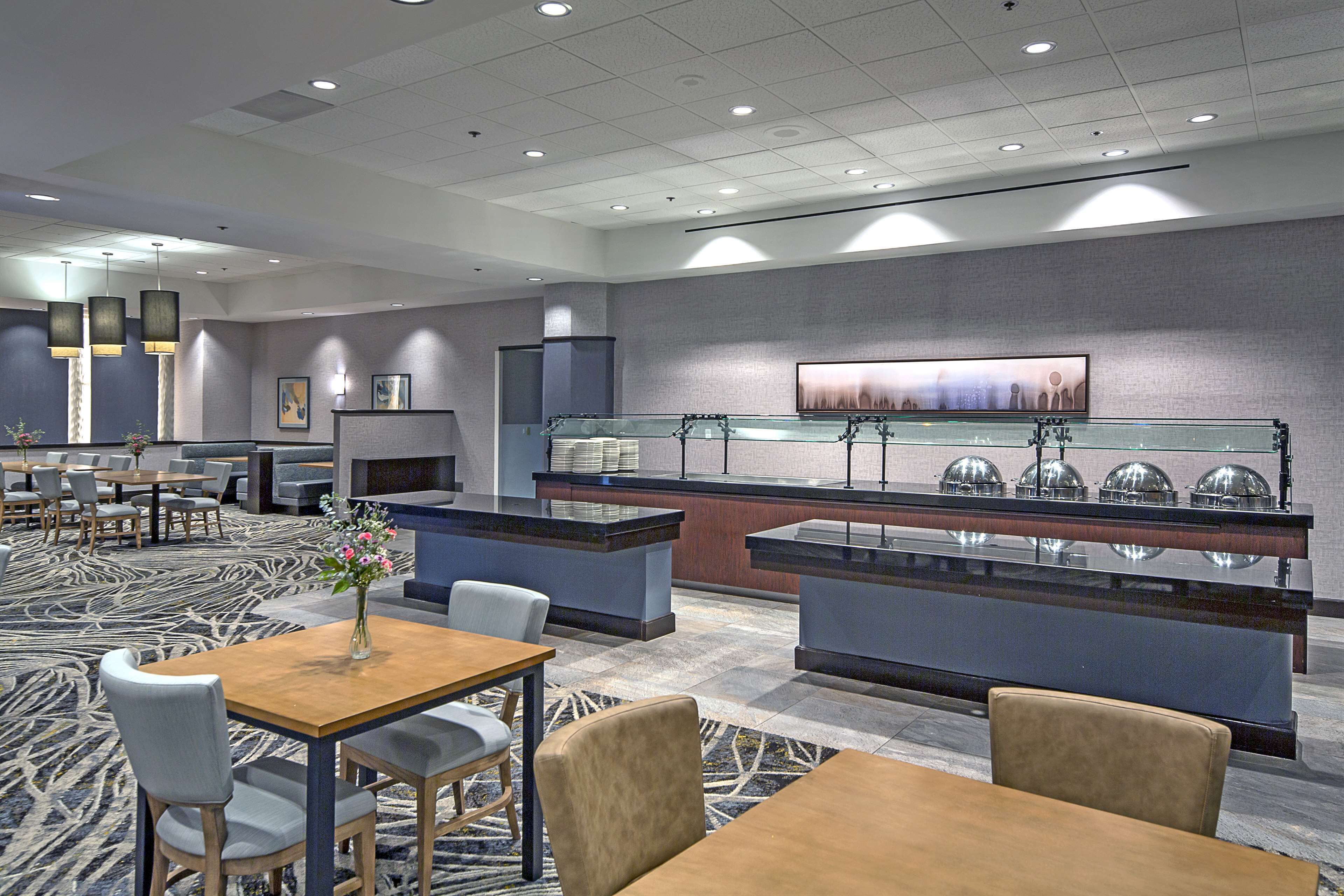 A modern hotel lobby with a reception desk, seating area, and buffet.