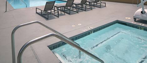 A swimming pool with a metal ladder, lounge chairs, and a lifeguard stand.