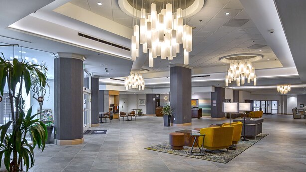 A spacious lobby with modern chandeliers, seating areas, and a reception desk.