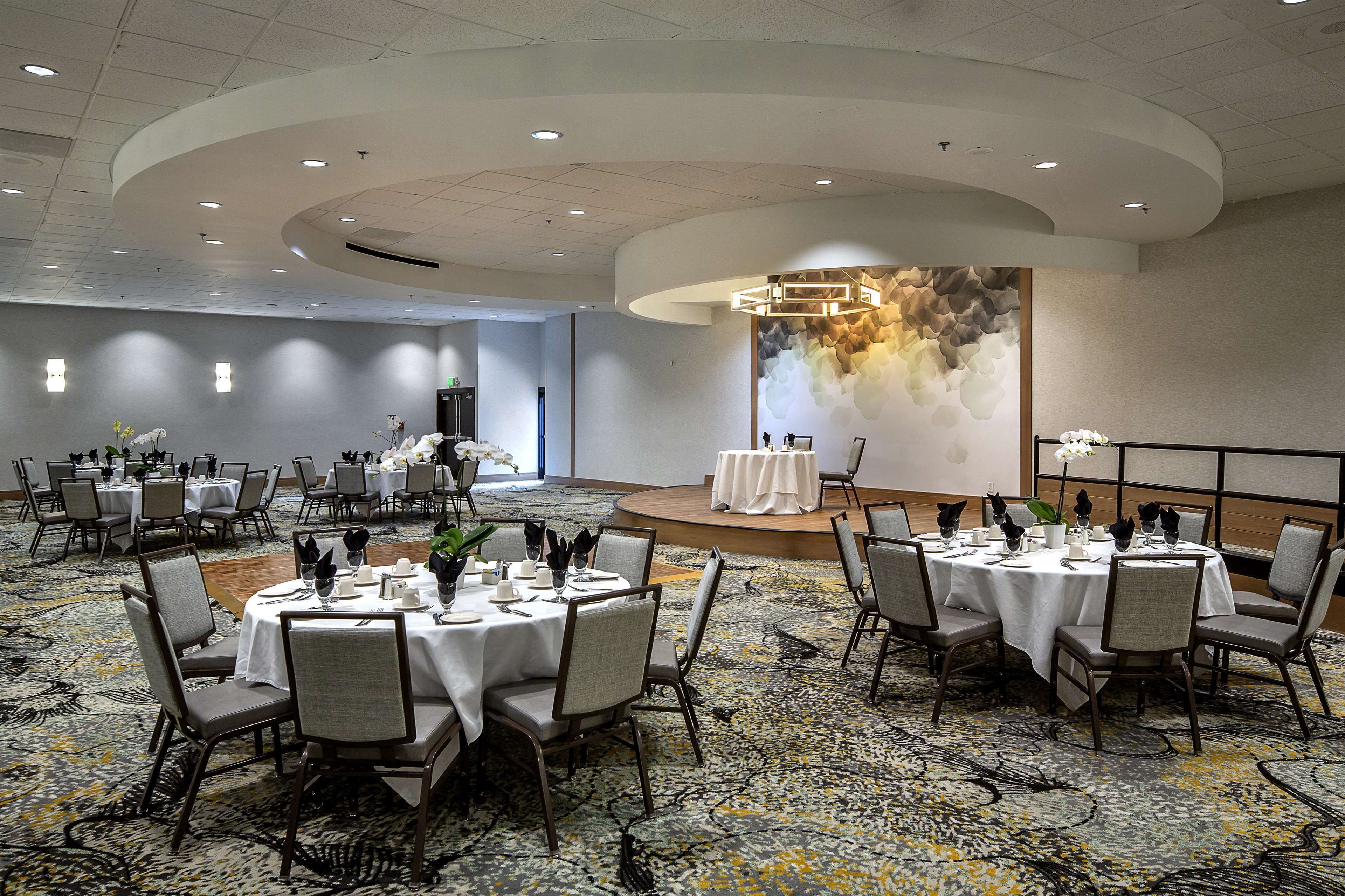 A conference room with round tables, chairs, and a stage.
