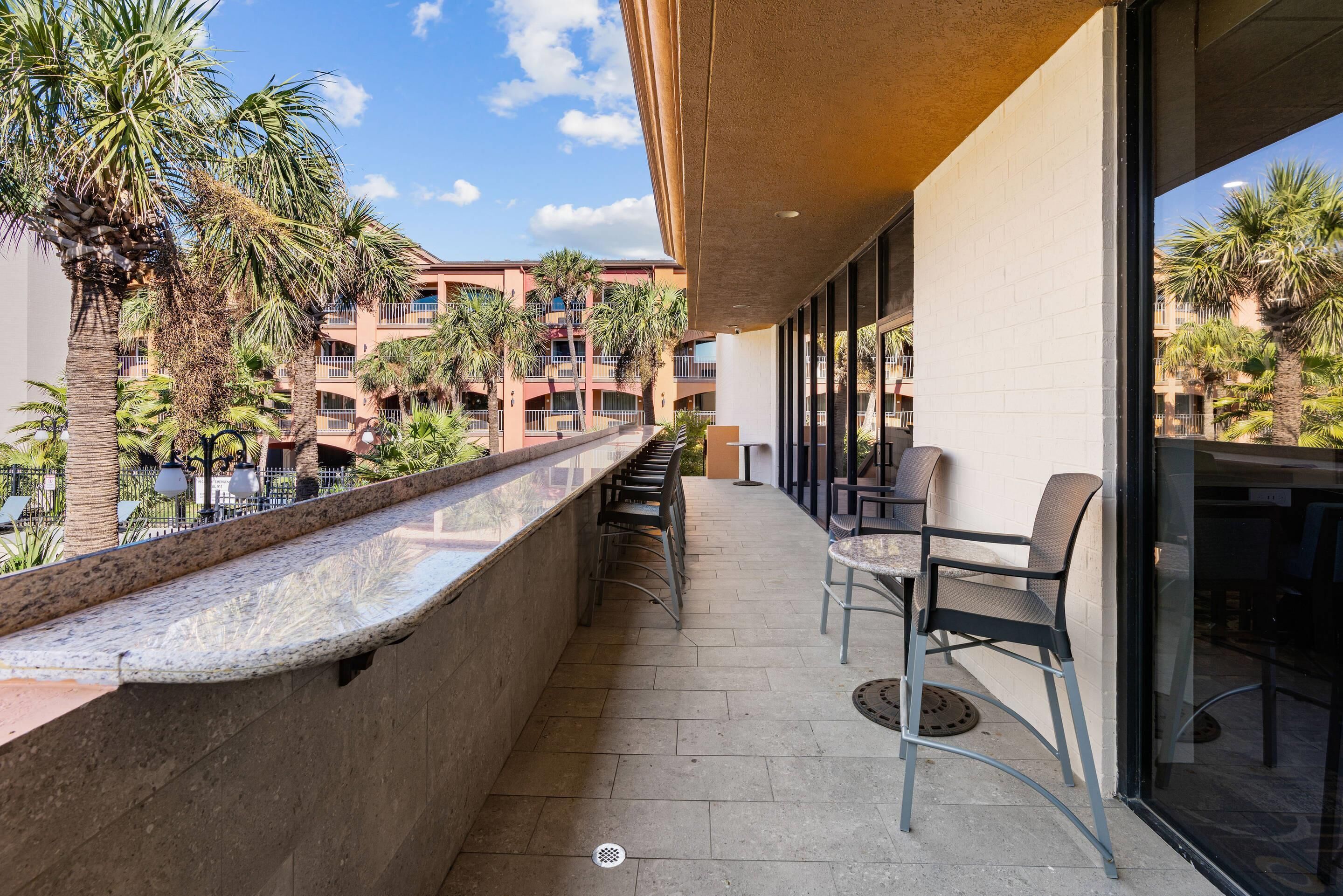 A balcony with a view of palm trees and a building with balconies.