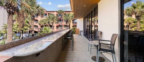 A balcony with a view of palm trees and a building with balconies.