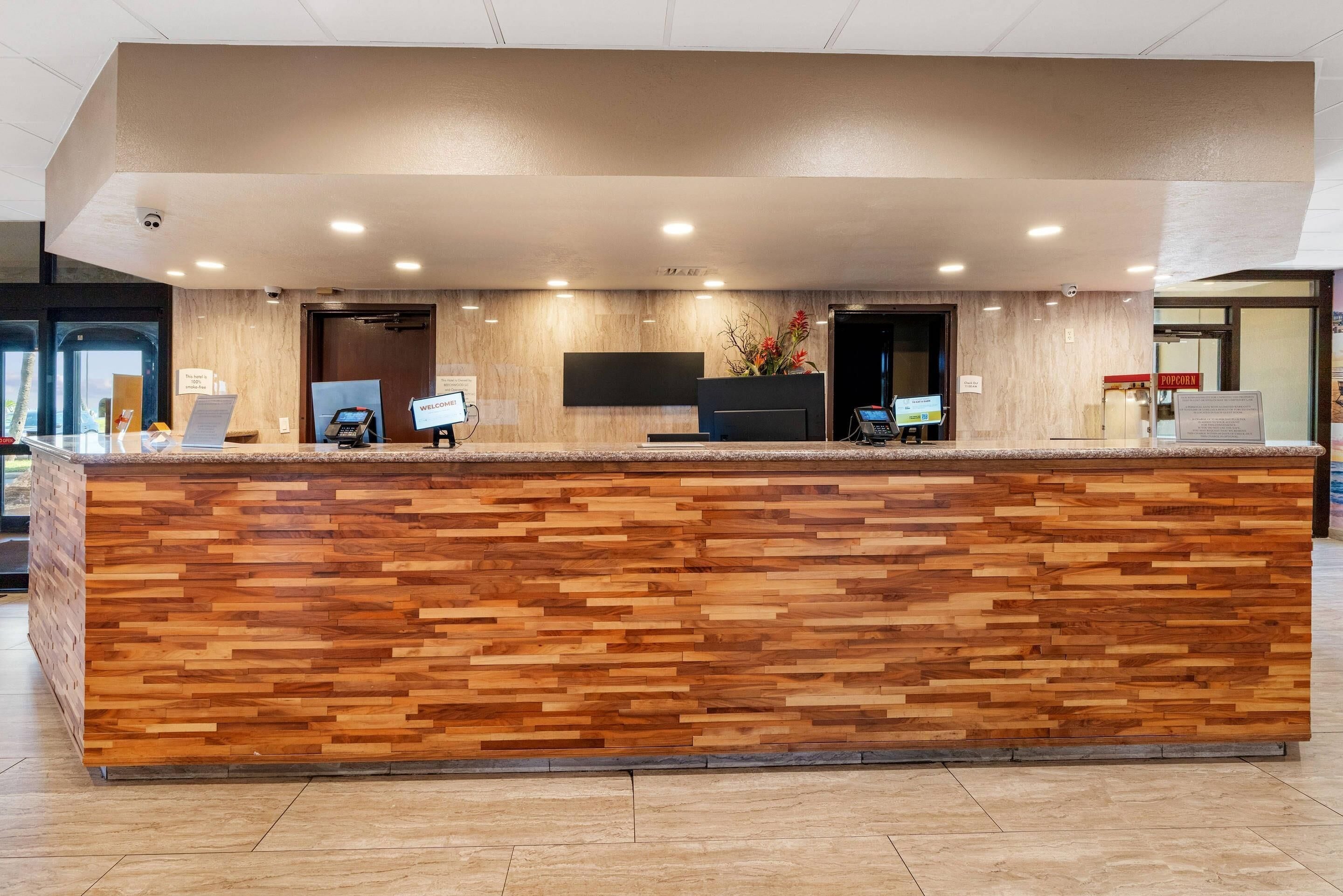 Een receptiebalie met een houten paneelontwerp, een flatscreen televisie en een digitale kiosk.