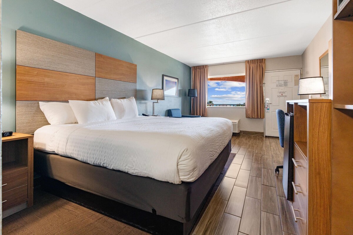 A hotel room with a large bed, bedside tables, a desk, and a view of the outdoors.